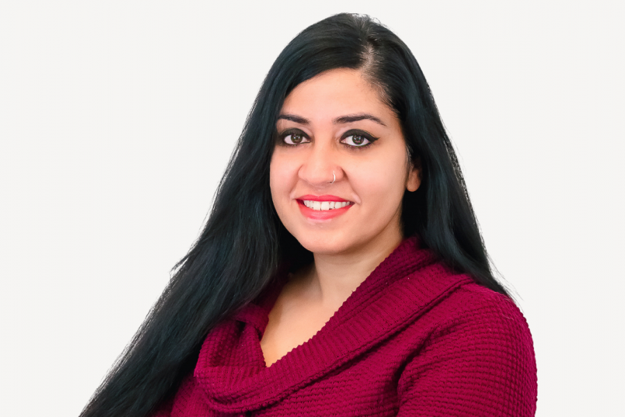 Smiling woman in a magenta sweater against a white background.