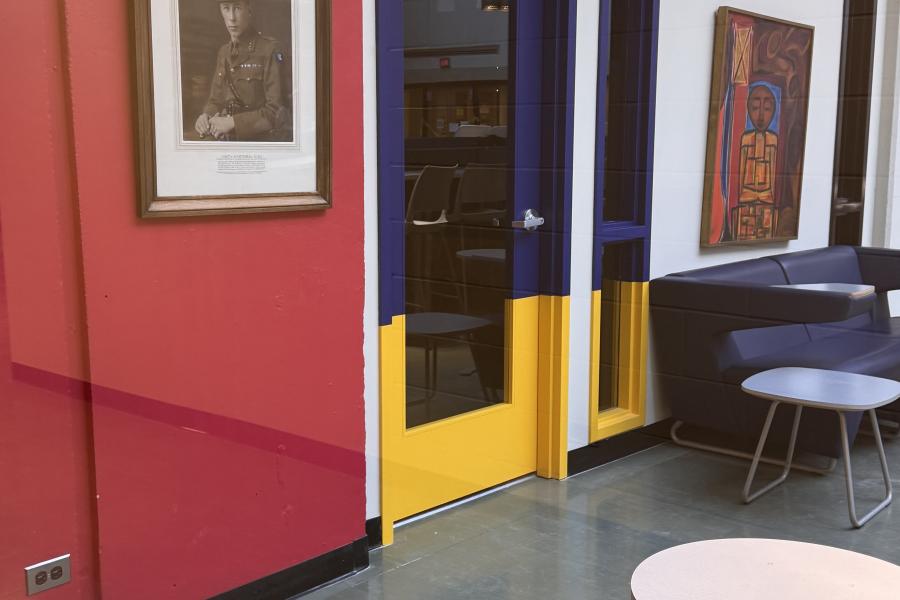 Interior view of the IDEA START Engineering Innovation Hub, featuring colourful blue and yellow doors, lounge seating, tables and artwork along the walls.
