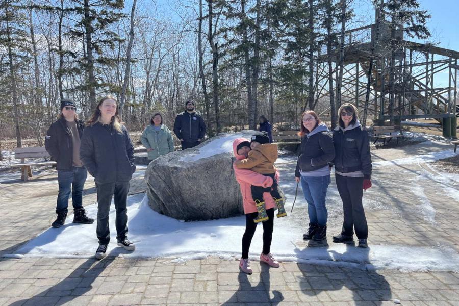 Group of people standing in front of a large rock at Fort Whyte Alive on a trip to see buffalo.