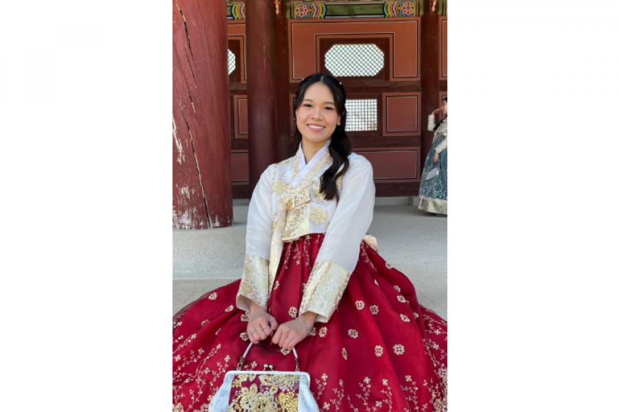 Cedey smiling at the camera dressed in a vibrant traditional-style dress.