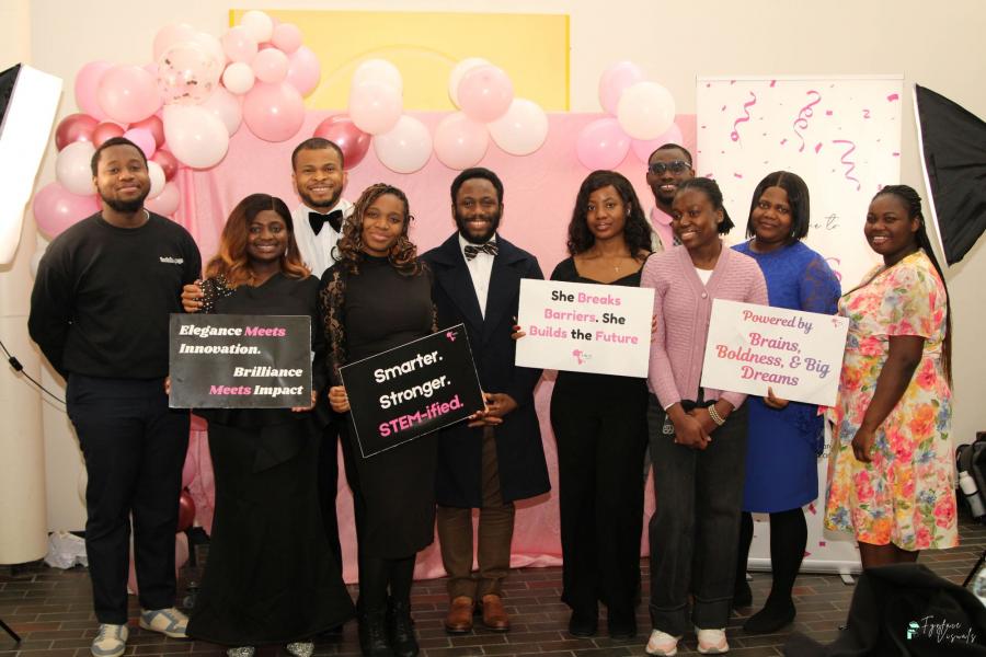 Individuals at a formal gala hold aspirational signs