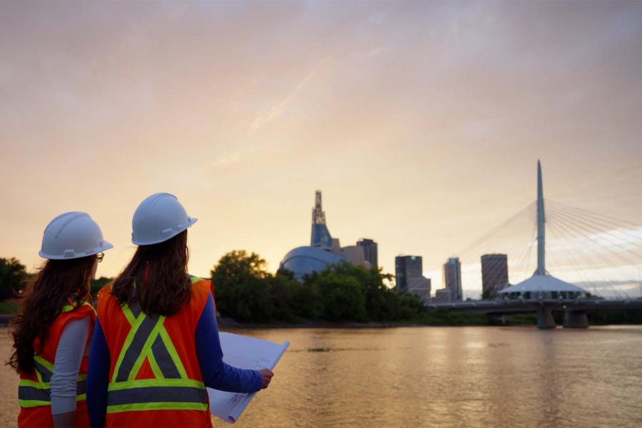Two engineers look across the river at the Winnipeg skyline