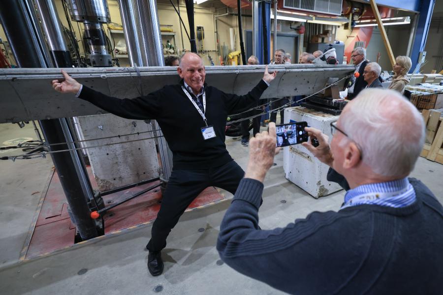 Civil Engineering student pretending to hold up concrete beam while classmate takes his photo