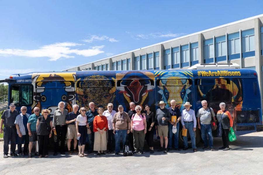 Architecture Class of 69-71 Group photo in front of UM branded shuttle bus