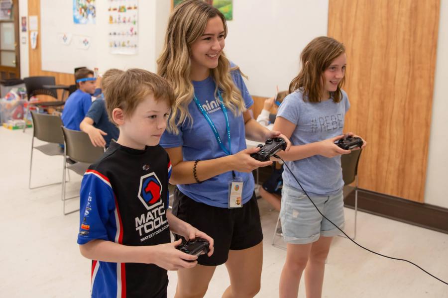 Two Mini U juniors play a video game with their leader.