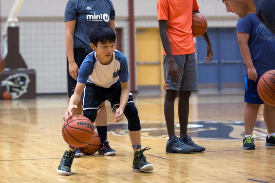 A Mini U junior dribbles a basketball during a game.
