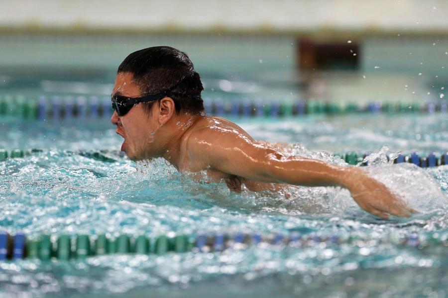 An adult swimmer swims laps while practicing the breaststroke.