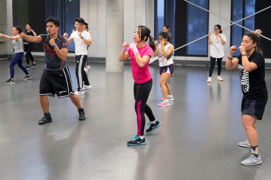 During a group fitness class members actively practice throwing jabs.