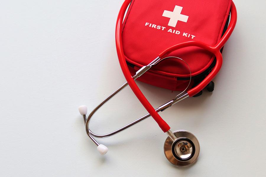 A photo of a red first aid kit and a red stethoscope.