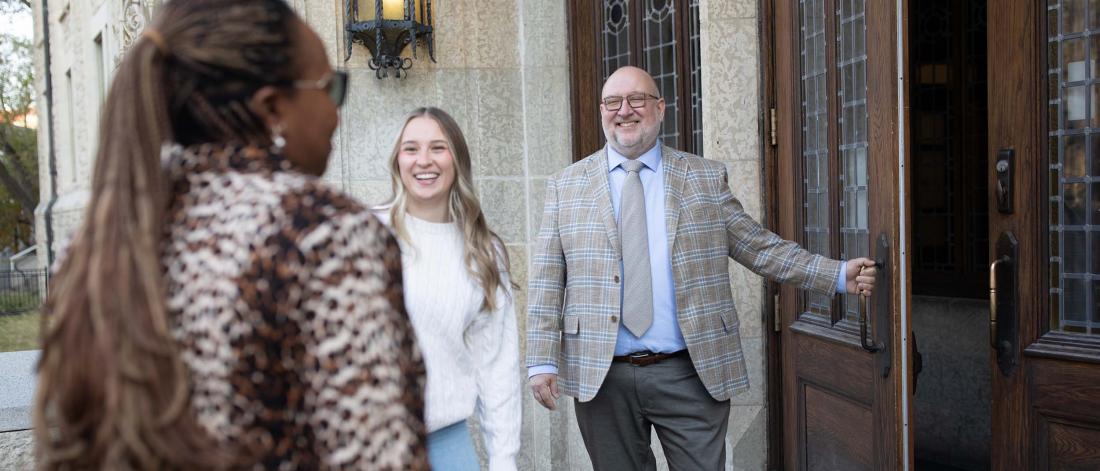 Dean Donahue opening the door for professor and student