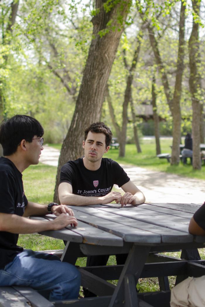 Residence dons sitting at a table outside with greenery around them