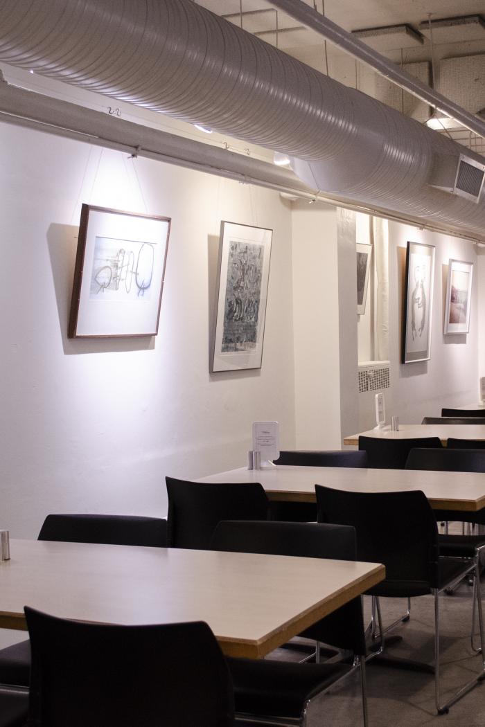 Photo of a restaurant with tables, a white wall and art pieces hung up