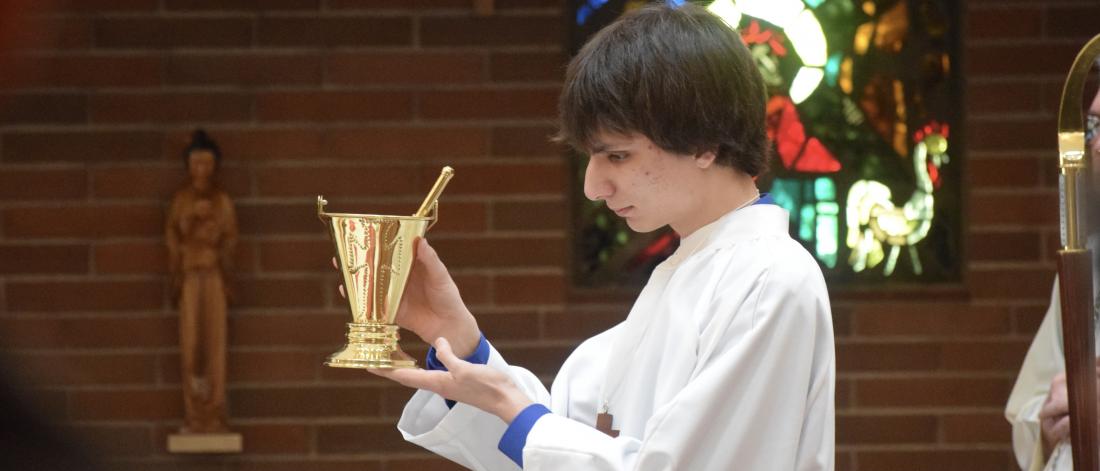 A student volunteers as an alter server at Mass for Campus Ministry 
