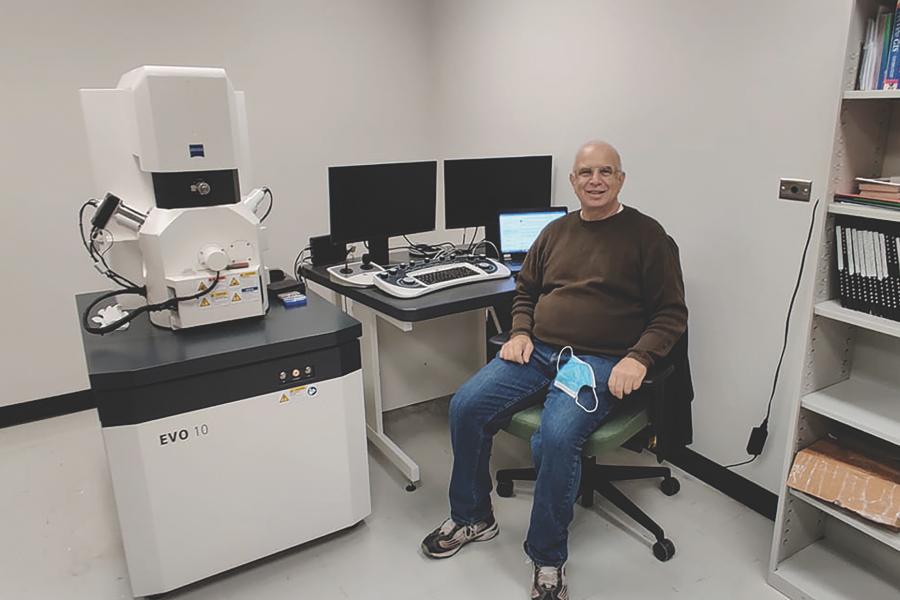 Professor in front of scanning electron microscope