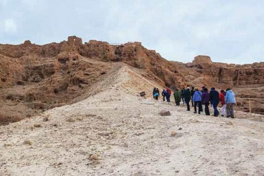Catholic pilgrims climbing a sandy gravel hill in the Holy land.