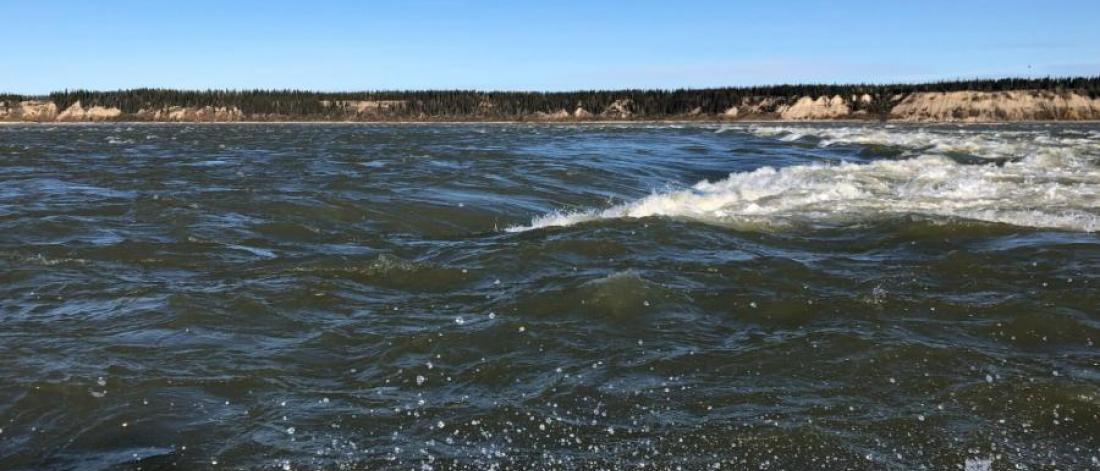 large body of water against a blue sky with a thin outline of the shore.