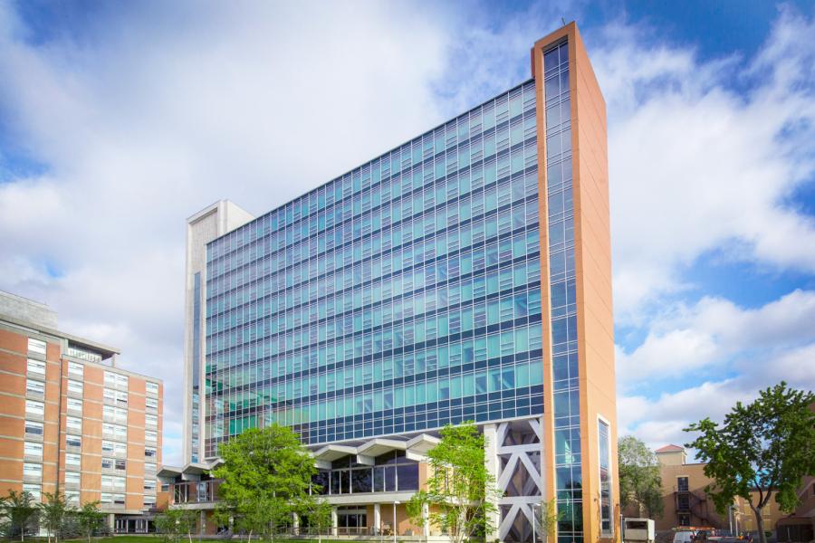 A blue sky and fluffy clouds are reflected into the glass exterior of the Pembina Hall building at the University of Manitoba Fort Garry campus.