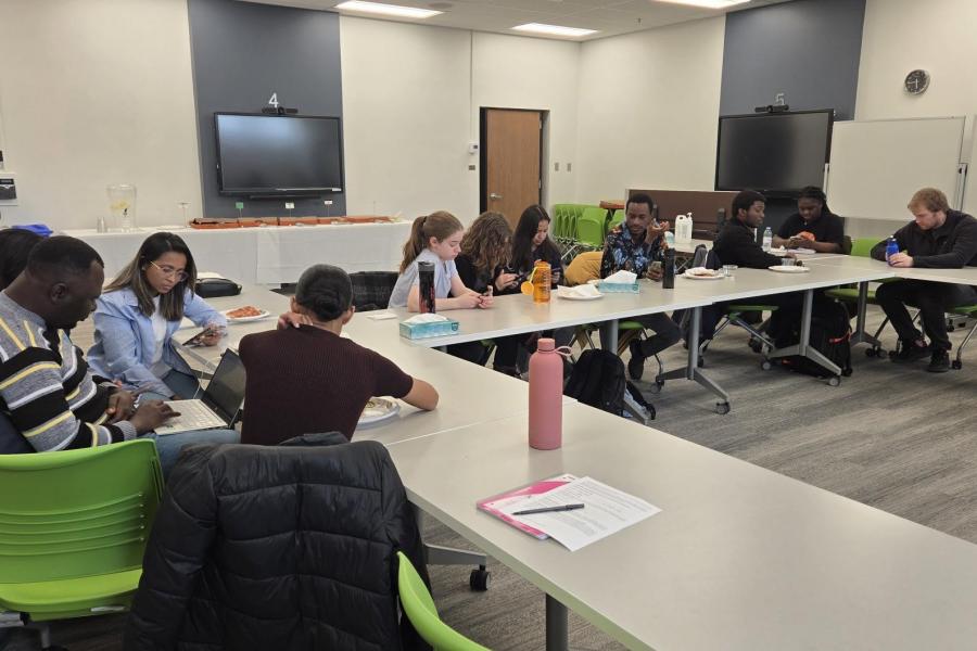 A group of people sitting at tables and writing on paper in a meeting room setting.